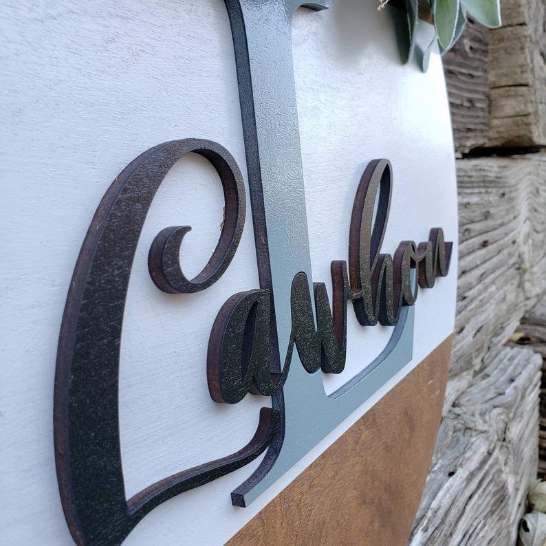 Raised 3D family name lettering on a personalized wooden door hanger
