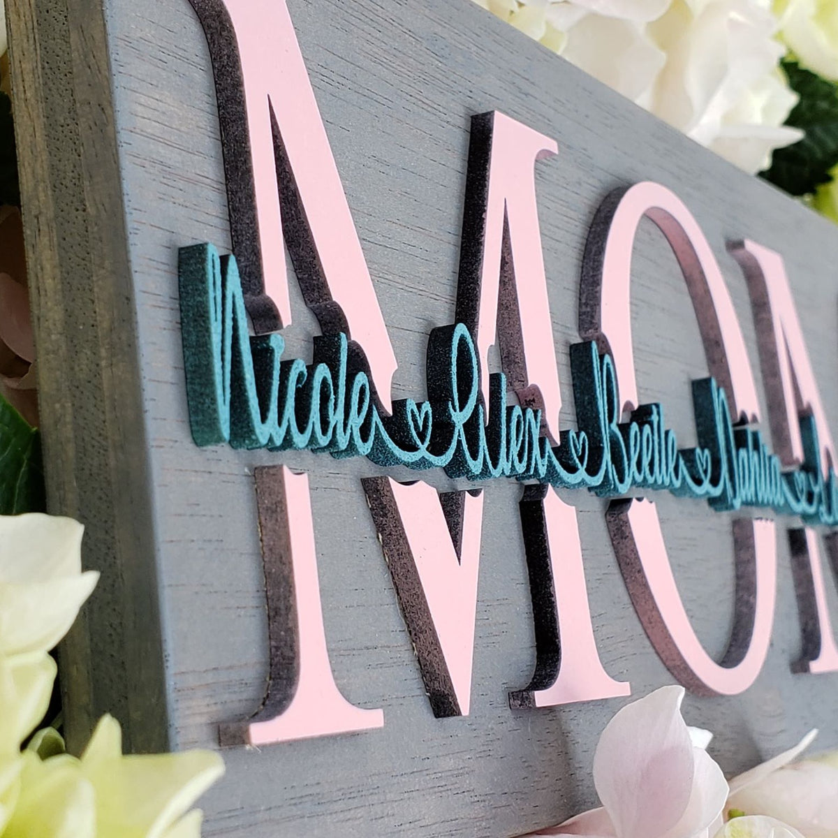Close-up of raised 3D names on a personalized wooden family sign