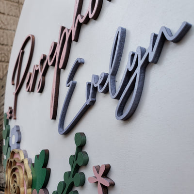 Close-up of raised 3D lettering and flowers on personalized nursery sign